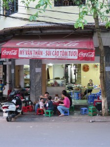 A common sight - meal time on the pavement on tiny tables and stools